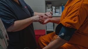 Correctional healthcare nurse is checking an inmate patients pulse and blood presure MK2